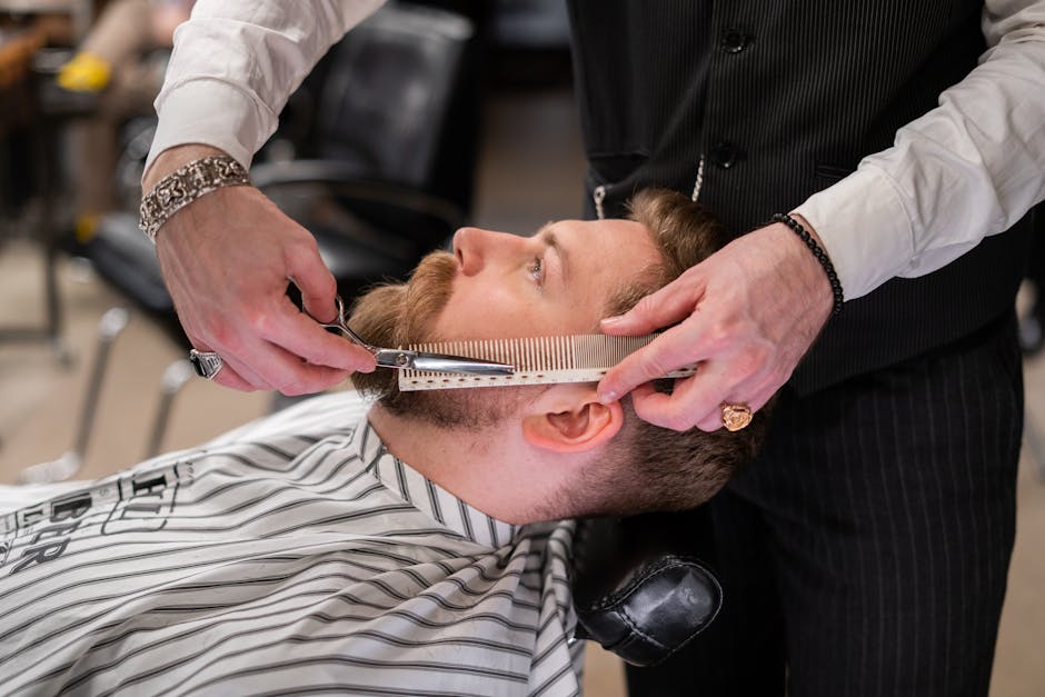 tea-tree-oil-seborrheic-dermatitis-guide-2026 - A skilled barber meticulously trims a client's beard using comb and scissors in a modern barbershop.